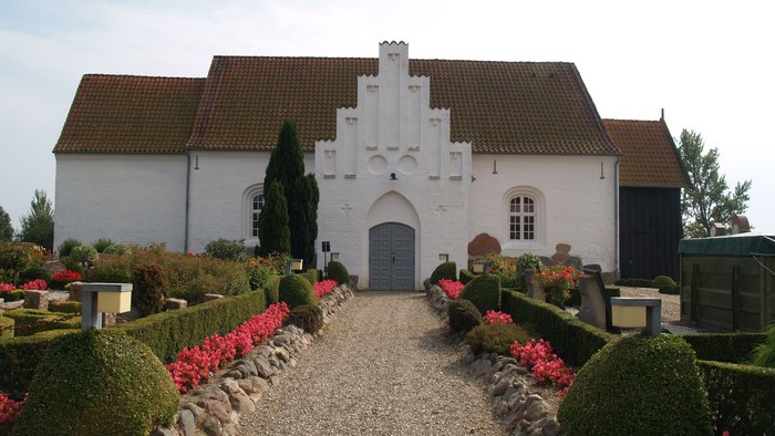 Et hvidt slot med tårn og røde blomster i have