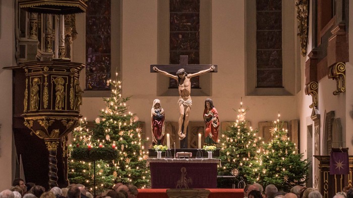 Ein Blick in die mit Weihnachtsbäumen festlich geschmückte Georgenkirche mit dem Stern über dem Altar