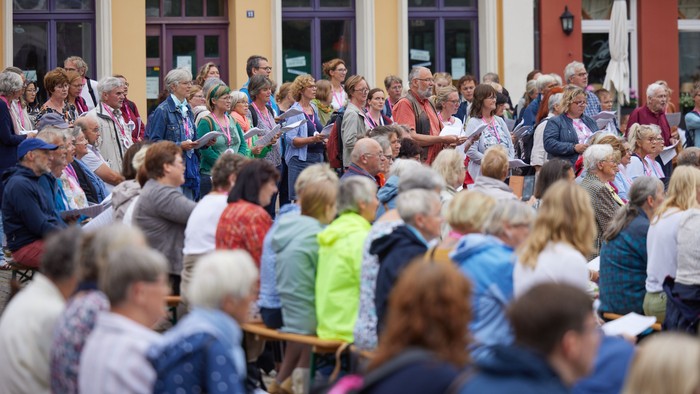 Eine große Menschenmenge versammelt sich im Freien in der Nähe eines Gebäudes mit der Aufschrift „Schwerin“ zu einer Veranstaltung oder Zusammenkunft.