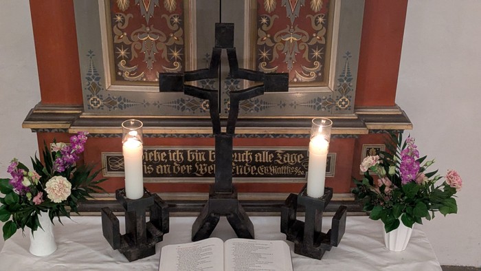 Altar mit Kreuz, zwei Kerzen und Blumen