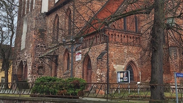 Gothische Backsteinkirche mit hohem Turm und Uhr.