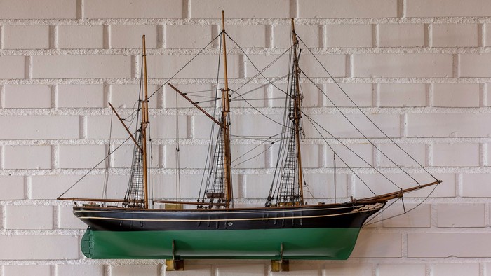 Et smukkt modelleret skib monteret på en hvid mursten.