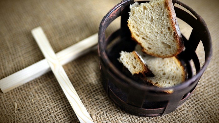 In einem kleinen Korb liegen zwei Brotscheiben auf einem Holztisch.