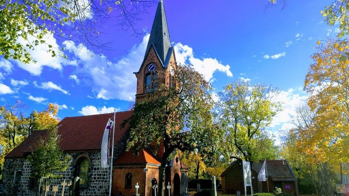 Kirchengelände mit hohem Turm und Herbstbäumen