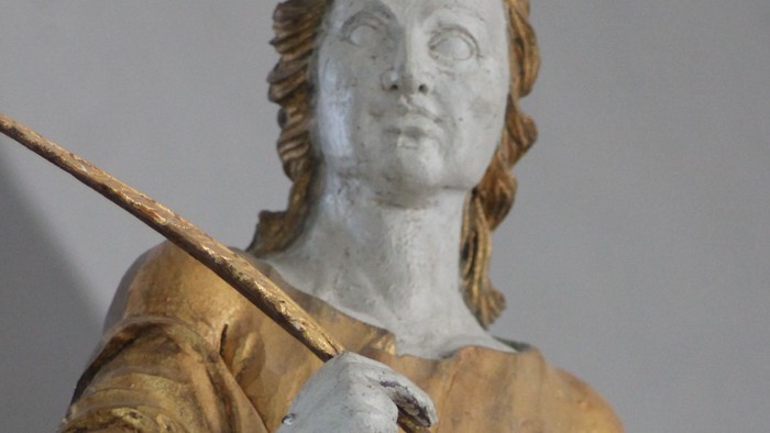 Guldstatue af kvinde med palmegren og bog.