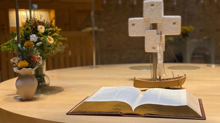 Bibel, kors og blomster i kirke