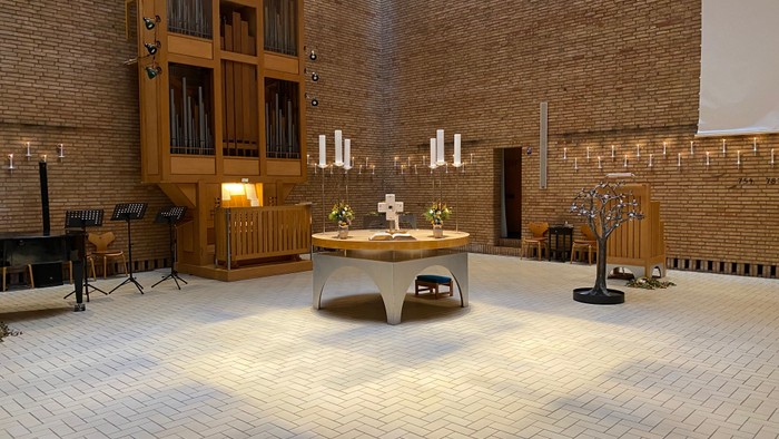 En stor kirkeindendelsesrum med bænke, alter og orgel.