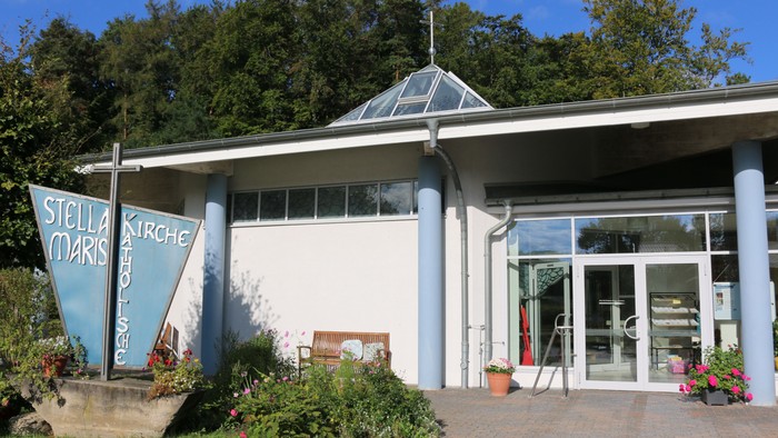 Das Bild zeigt ein Restaurant mit großem Glasfenster und einem blauen Schild mit der Aufschrift 