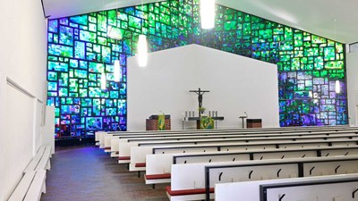 Die Kirche hat bunte Glasfenster und weiße Bänke