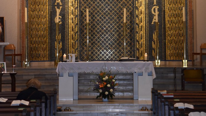 Der Altar einer Kirche mit Kreuz und Blumen.