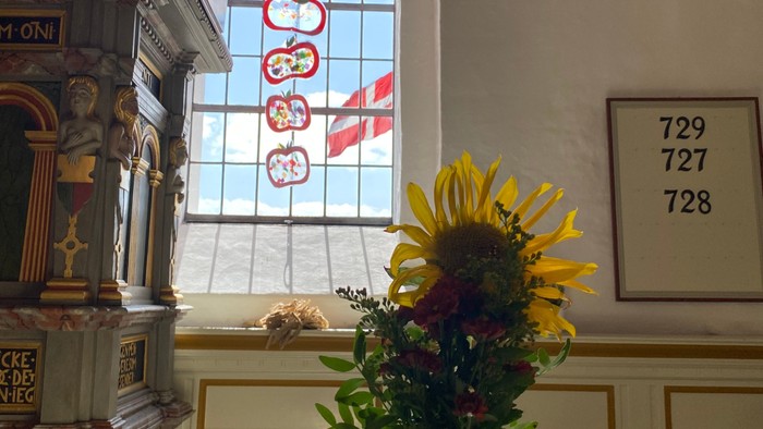 Solsikkebuket i en kirke ved siden af et farvet glasvindue