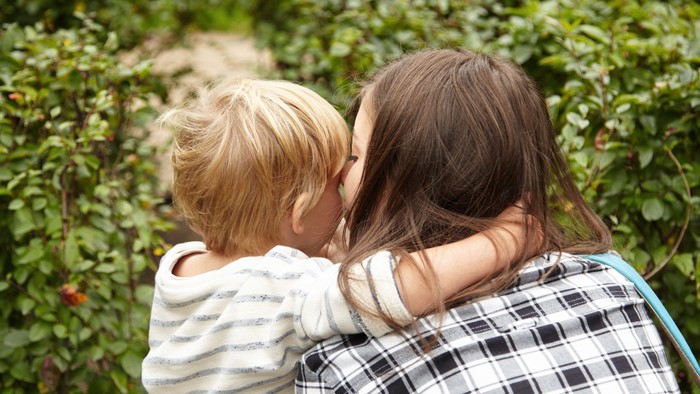 Eine Frau hält einen jungen Jungen in einer grünen Umgebung im Freien.