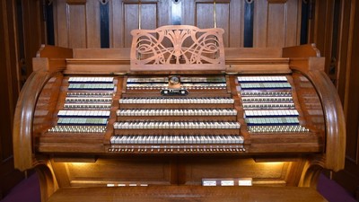 Ein hölzernes Kirchenorgel mit mehreren Tastaturen und Fußpedalen.