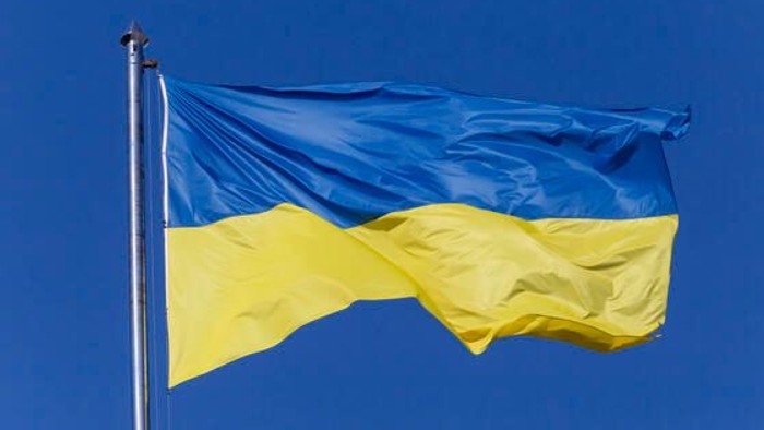 Blå og gule flag waver i blå himmel