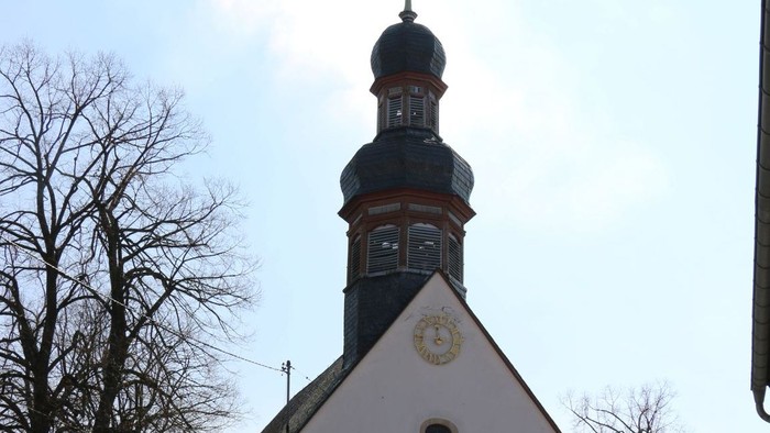 Kleine weiße Kirche mit schwarzem Turm und Kreuz auf dem Dach.