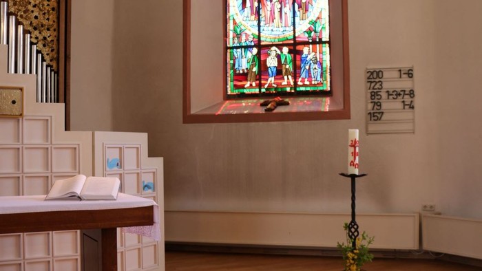 Kircheninneres mit Buntglasfenster und Kerze.