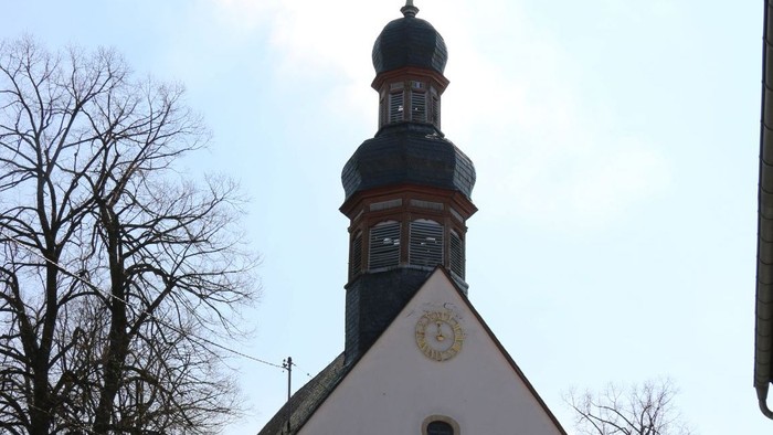 Kleine weiße Kirche mit schwarzem Turm und Kreuz auf dem Dach.
