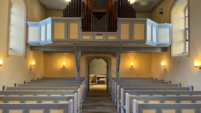 Leere Kirchenbankreihen vor einer Orgel