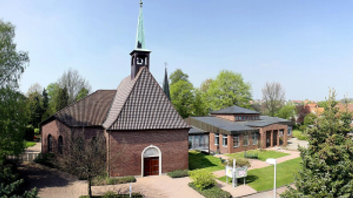 Das Bild zeigt eine Kirche mit hohem Turm und umgebendem Garten.