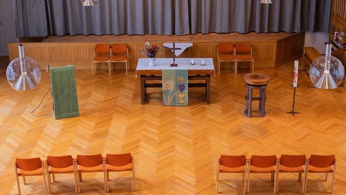 Ein Auditorium mit Holzboden, Bühnenbestuhlung, Podium und dekorativer Beleuchtung.