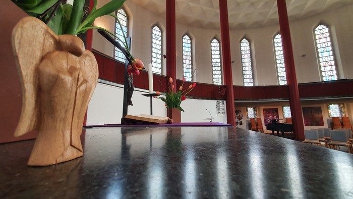 Ein Kircheninneres mit großen Fenstern und Blumenarrangements