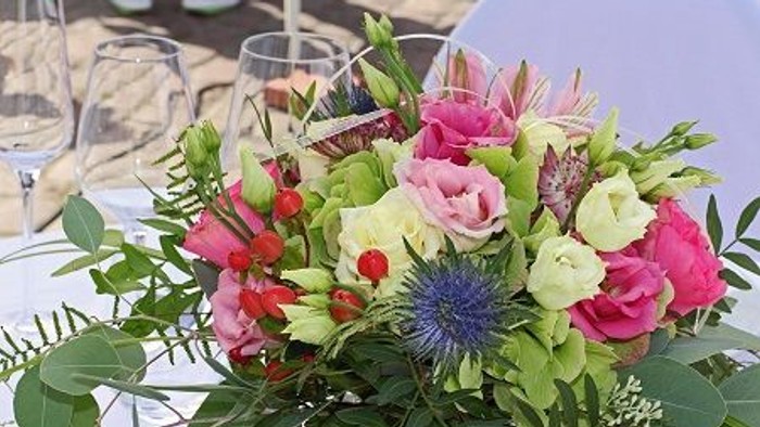 Ein farbenfroher Blumenstrauß auf einem Tisch mit Gläsern im Hintergrund