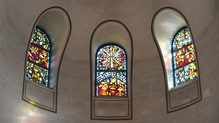 Bunte Glasfenster in gewölbten Nischen zeigen aufwendige religiöse Motive in leuchtenden Farben.