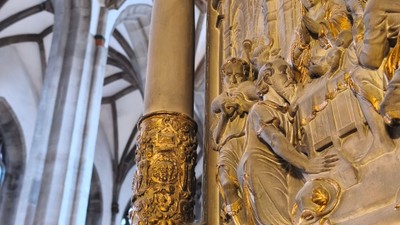Komplexe goldene Reliefskulptur mit biblischen Figuren im Inneren einer prächtigen Kathedrale.
