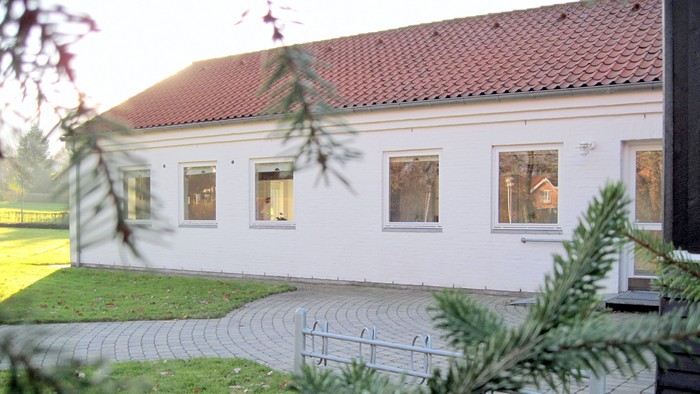 Hus med rødt tag og hvide vinduer.