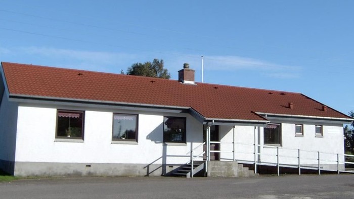 En hvid hytte med rødt tag og en trappe til indgangen.