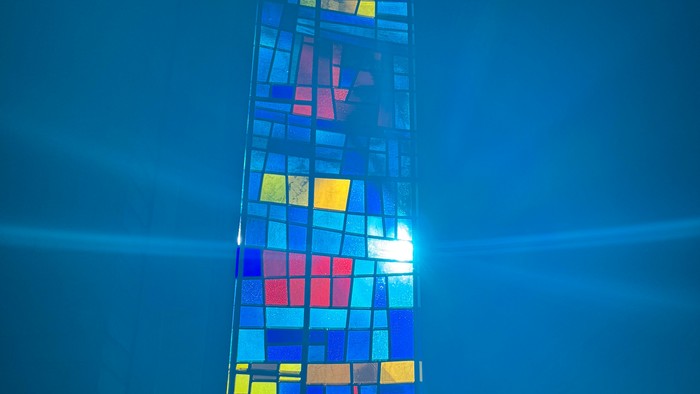 Lebendiges Mosaik-Fenster aus Buntglas mit farbenfrohen geometrischen Mustern, von hinten beleuchtet.