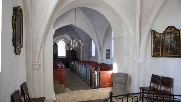 Indgang til kirke med bænke og billeder.