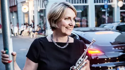 Frau spielt Flöte auf belebter Straße