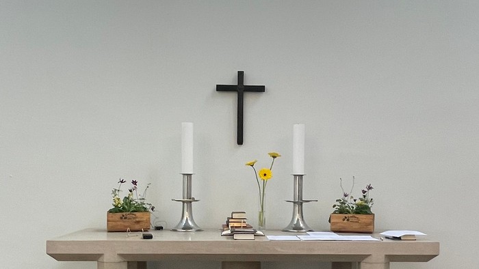 Elegant kapelinteriør med farvet glas, alter, lys og skandinaviske flag på hver side.