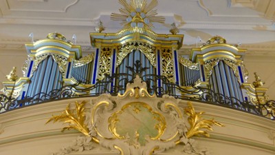 Prächtige Orgel mit goldenen Verzierungen und filigranem Design in einem prunkvollen Raum.