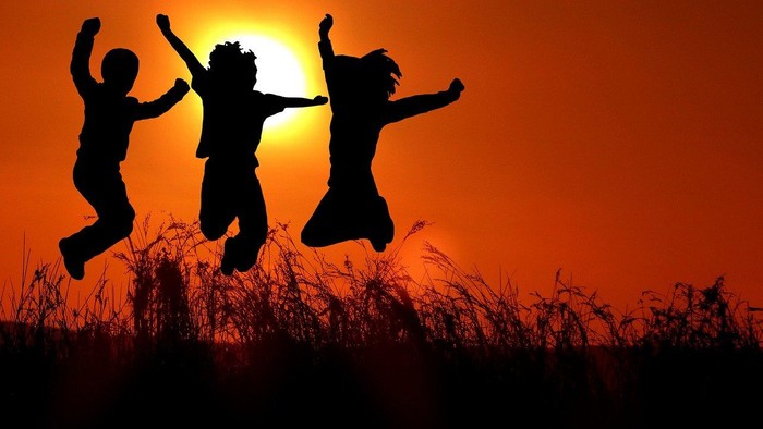 Three people jumping in the air at sunset.