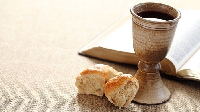 A chalice and pieces of bread on a tablecloth