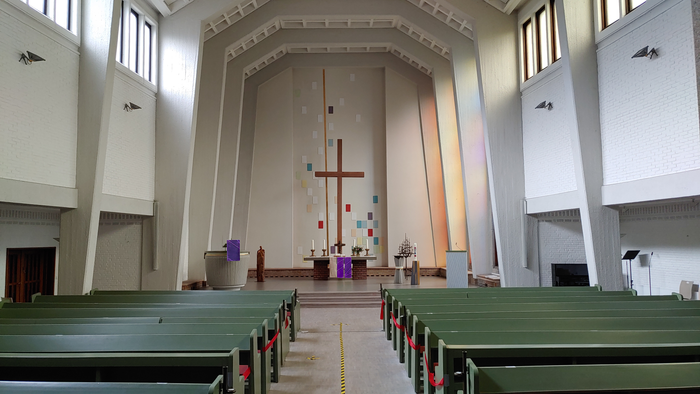 Die Kirche hat eine große Holzkanzel und ein hohes Kreuz im Altarraum.