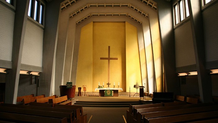 Innenraum einer Kirche mit Kreuz und Kirchenbänken