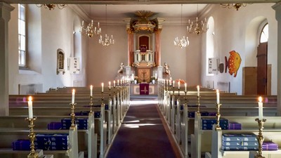 Blick auf den Altarraum in der Dorfkirche Lübars mit angezündeten Kerzen