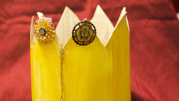 Gelbe Krone mit Edelsteinen auf rotem Stoff