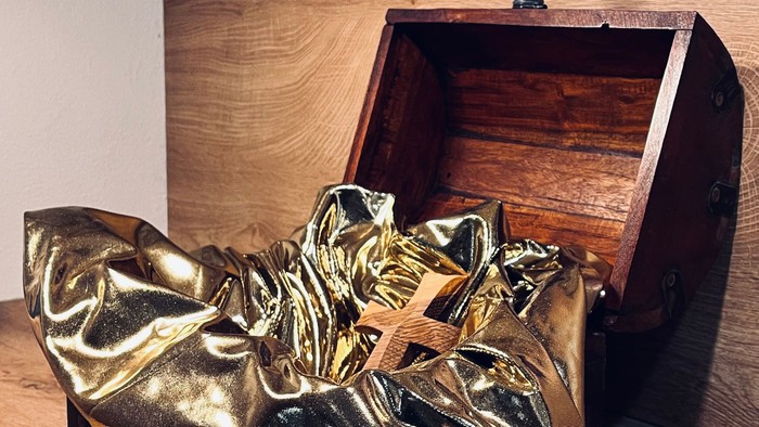 Goldene Stiefel vor einer Holztruhe