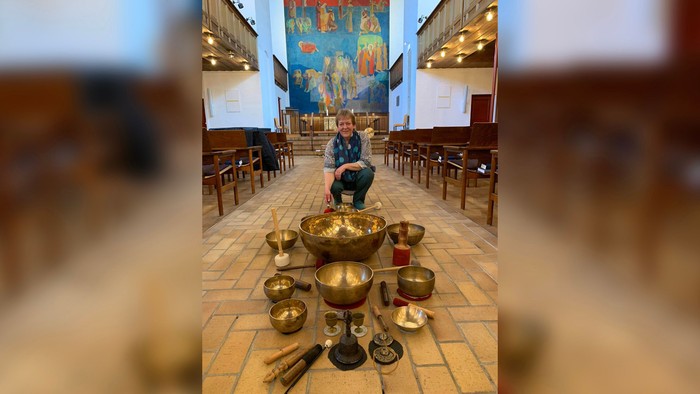 En kvinde sidder i en kirke med en rekke buddhistiske klokker foran sig