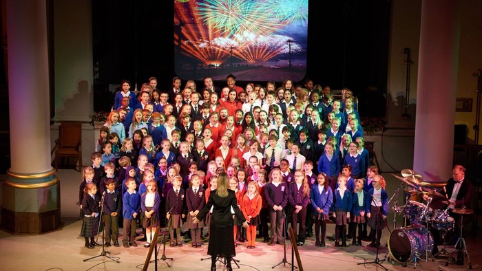 Large group of children on stage with colorful background.