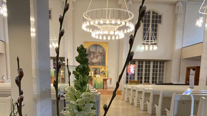 Elegante Blumenarrangement in der modernen Kirchenlobby mit einer Zeitschriftenauslage auf einem Tisch.