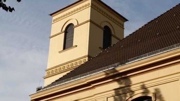 Eine historische Kirche mit einem hohen Glockenturm und Bogenfenstern unter einem klaren Himmel.