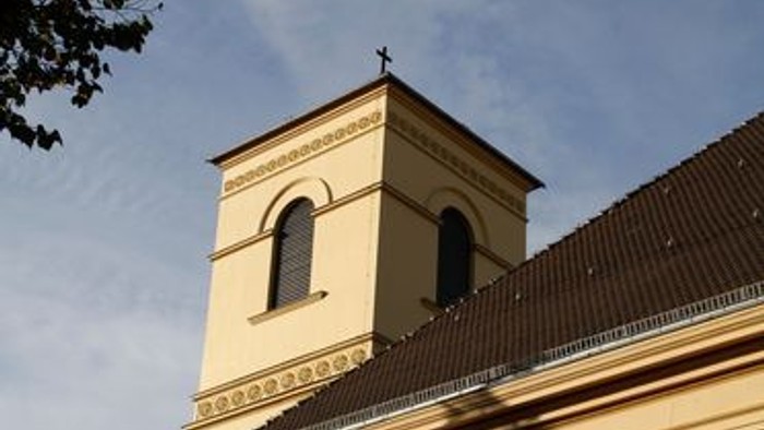 Eine historische Kirche mit einem hohen Glockenturm und Bogenfenstern unter einem klaren Himmel.