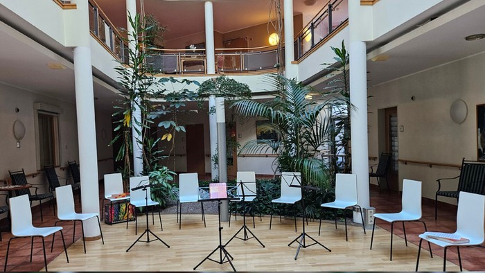 Modernes Innenatrium mit zwei Ebenen Sitzbereichen, umgeben von üppigem Grün und stilvollen Möbeln.