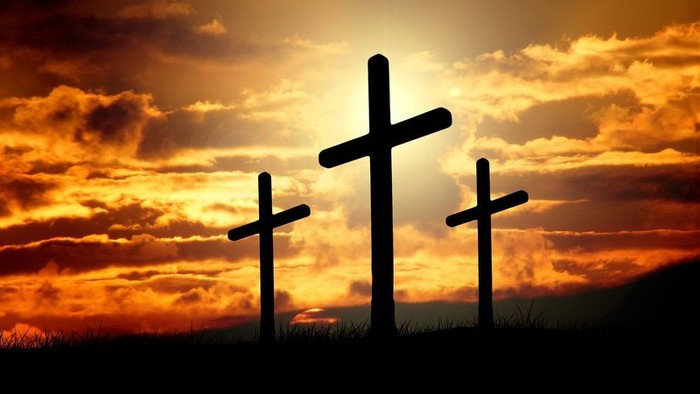 Tre kors stiger op mod en solrød himmel.