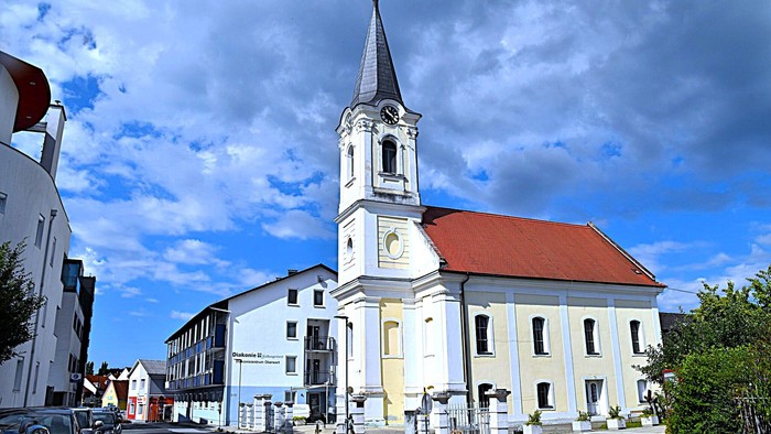 Kirchengemeinde mit weißem Turm und rotem Dach in kleiner Stadt